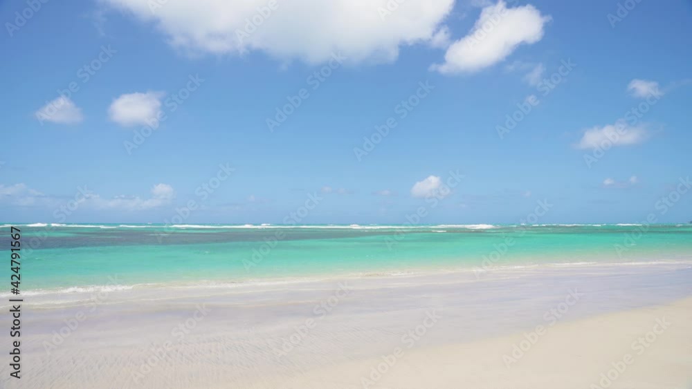 White sand of tropical beach turquoise sea waves and blue cloudy sky. Summer seascape of the Caribbean coast of the Dominican Republic. Good weather for travel and recreation. White sand of tropical beach turquoise sea waves and blue cloudy sky. Summer seascape of the Caribbean coast of the Dominican Republic. Good weather for travel and recreation.