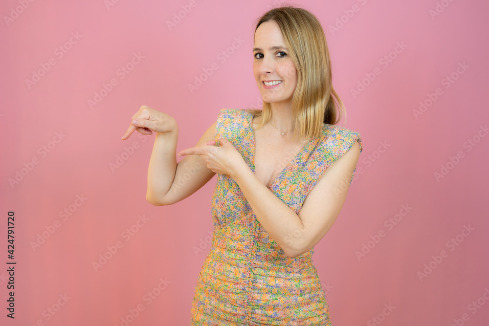 Young woman wearing casual dress over isolated pink background pointing fingers to the side Young woman wearing casual dress over isolated pink background pointing fingers to the side