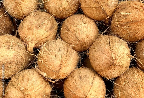 Heap of peeled brown coconut cocos nucifera kept for sale. Coconut fruits kept for sale in the market. Coconut fruits arranged in the market stall for sale.