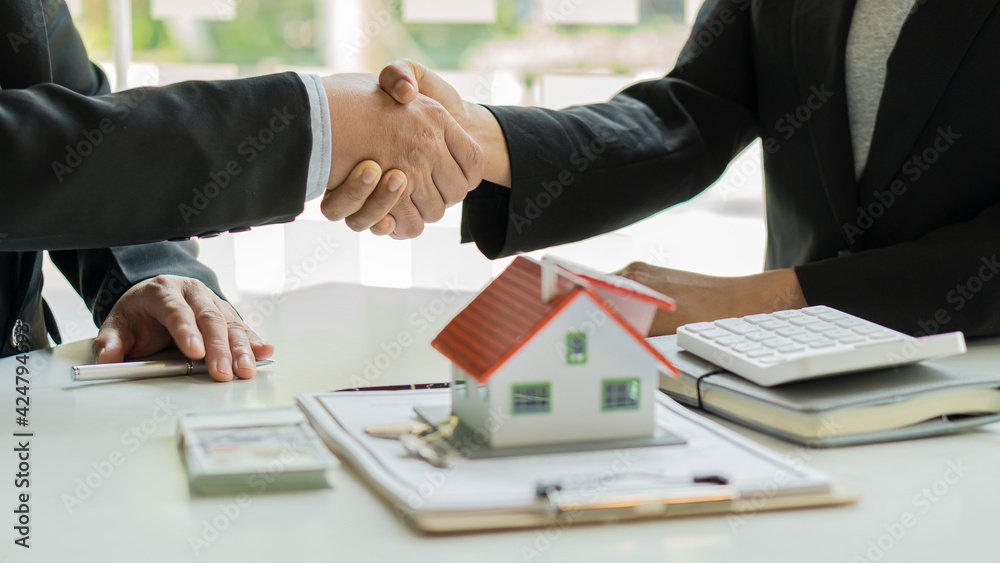 Real estate agent shakes hands with client after signing home purchase agreement after Finan has passed.