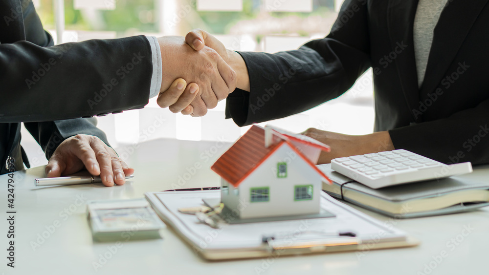 Real estate agent shakes hands with client after signing home purchase agreement after Finan has passed. Real estate agent shakes hands with client after signing home purchase agreement after Finan has passed.
