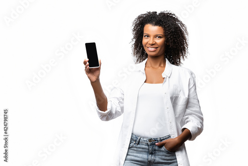 Smiling african american woman holding smartphone with blank screen isolated on white
