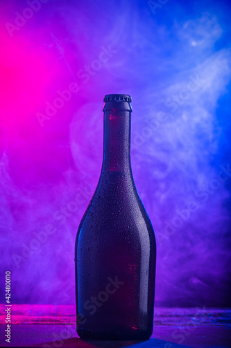 A ottles of beer on colorful smoke dark background