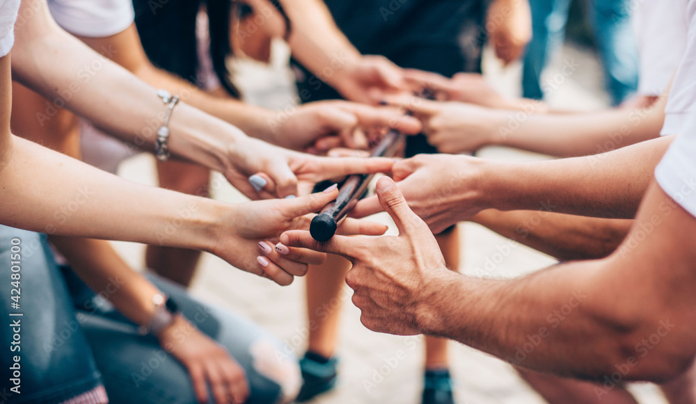 Obraz premium Close-up of the hand of people who are holding 1 stick all together. Team building event
