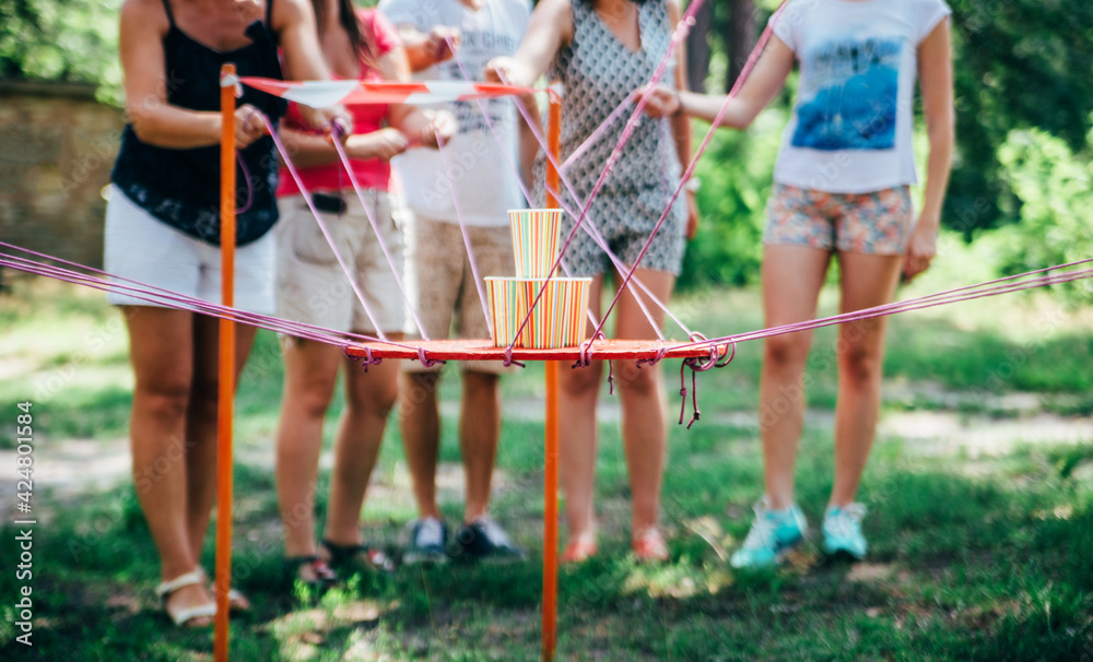 A group of people at work perform a team-building exercise, carrying glasses of water, using threads