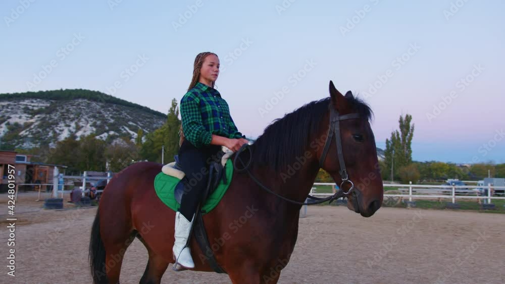 A teenage cowgirl on the horseback. A young rider sitting astride at the paddock