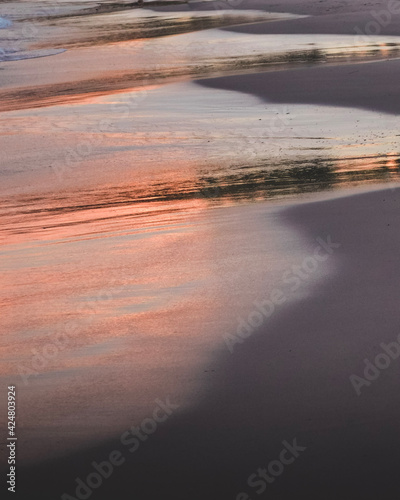 Reflection of the sunset on the water and sand of the beach