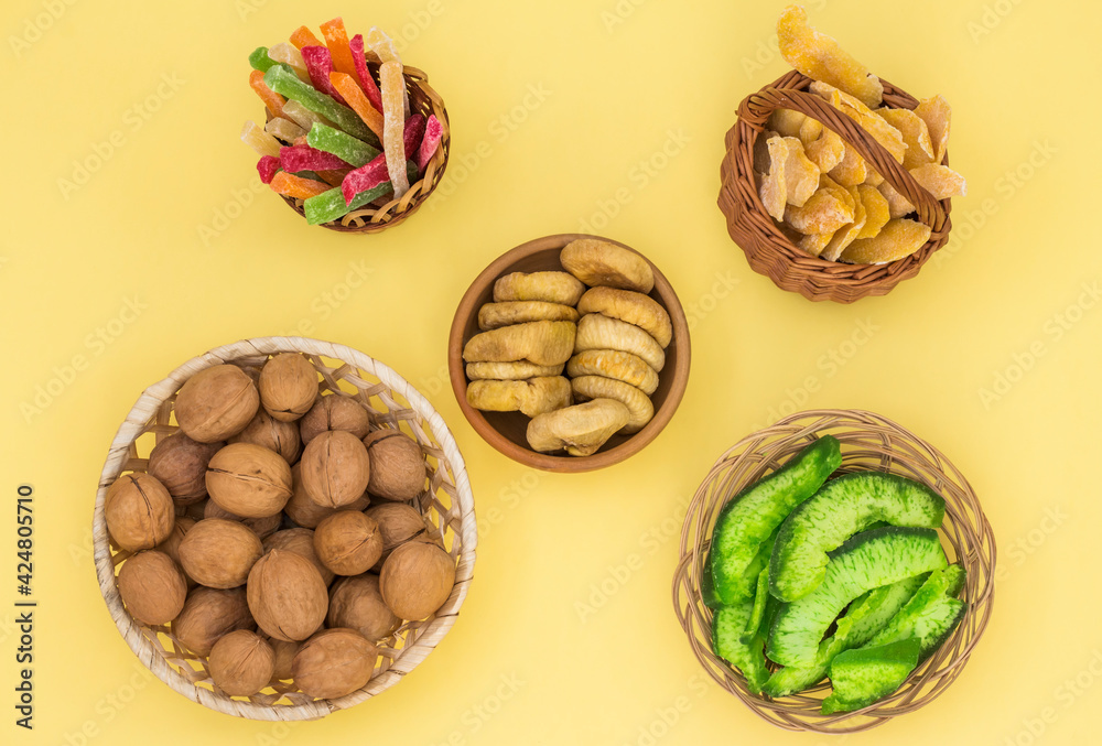 nuts and dried fruits in round plates and baskets on a yellow background nuts and dried fruits in round plates and baskets on a yellow background