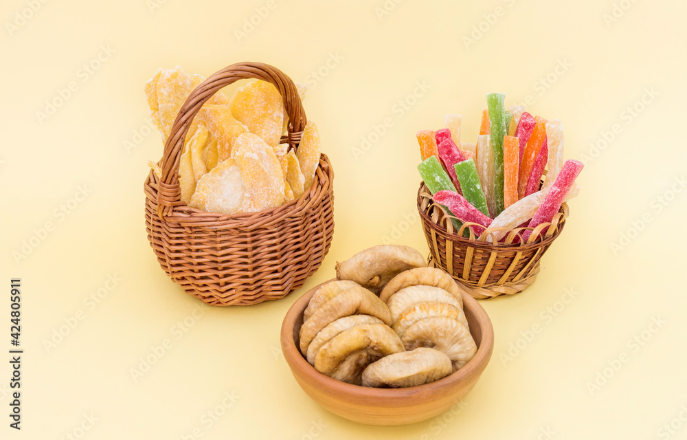 dried fruits mango in a basket figs in a cup and sticks of colored pineapple