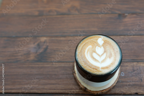 Coffee cappuccino on wooden table. Close up shot on a coffee cup against wooden background. Cup of coffee with latte art on wooden table. Cappuccino on vintage wood.
