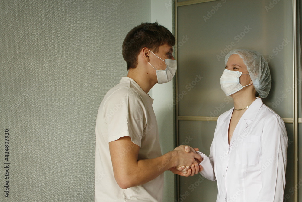 Obraz premium Female doctor greets and shakes hands with male patient during meeting in medical office.