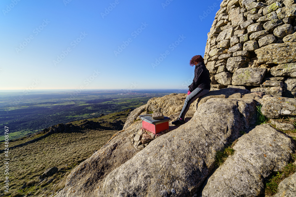 Woman at the top of the mountain contemplating the views after reaching the top.