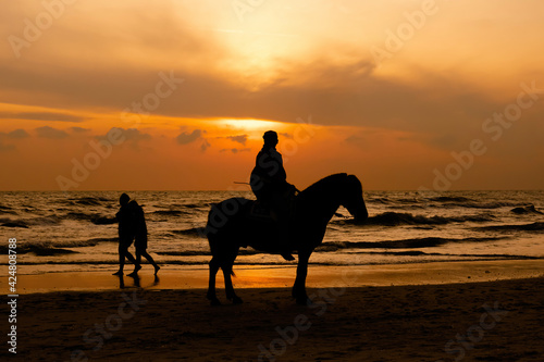 A silhouette of a horse riding a horse on Hua Hin Beach, Thailand