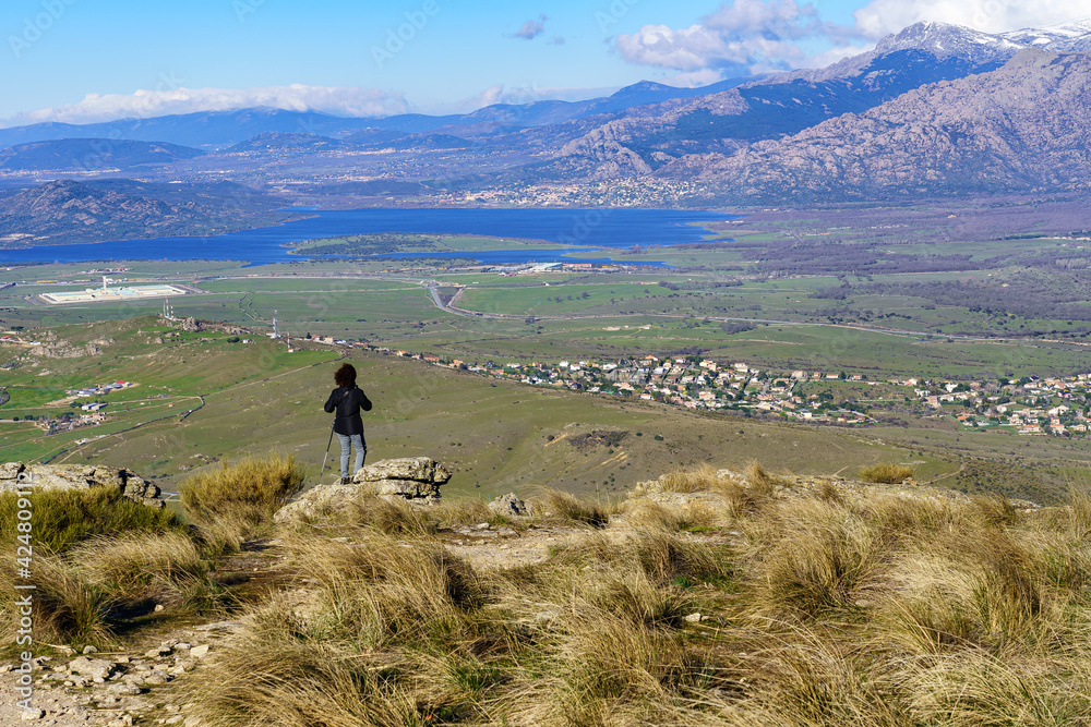 Obraz premium Woman hiking up the mountain paths to the top, with beautiful views of the landscape in the background.