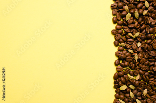 Fragrant сoffee beans, cardamom on a yellow background. Place for your text.