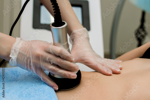 A woman in a beauty salon receives a vacuum abdominal massage, Hardware cosmetology.