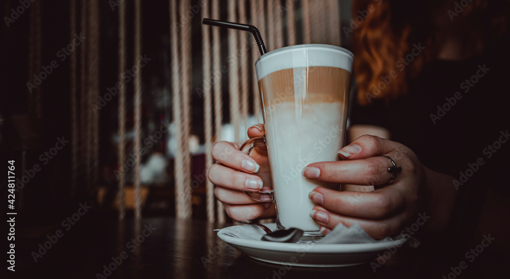 Female hands hold a glass of flat white coffee in caffee Female hands hold a glass of flat white coffee in caffee