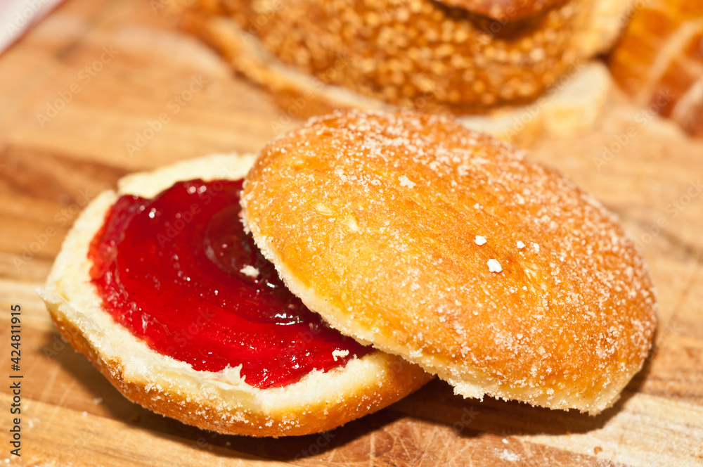 top view, close upon a freshly baked donut =,cut in half and filled with raspberry reserves on a wood serving plate top view, close upon a freshly baked donut =,cut in half and filled with raspberry reserves on a wood serving plate