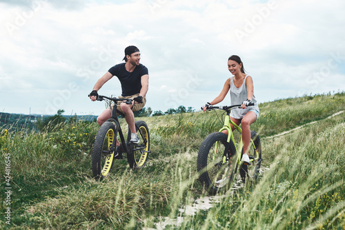 A man and a woman are laughing and riding fatbikes