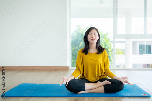 Asian women are doing yoga at home to make a good body.