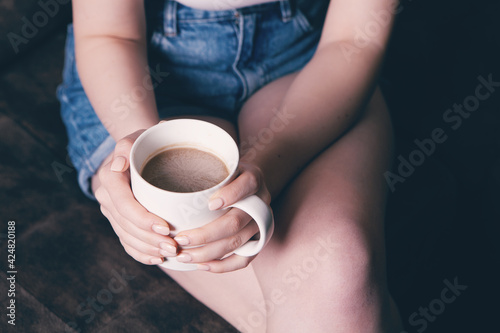 Close-up of female hands with a mug of drink.