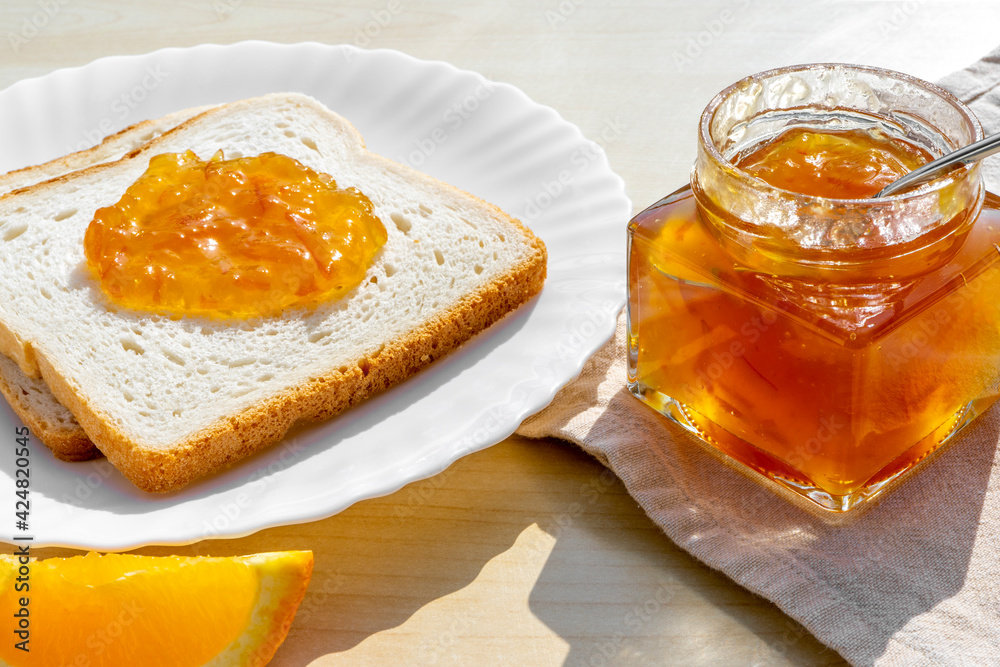 Slices of bread toast with homemade orange jam for breakfast on a wooden background. Breakfast concept Slices of bread toast with homemade orange jam for breakfast on a wooden background. Breakfast concept