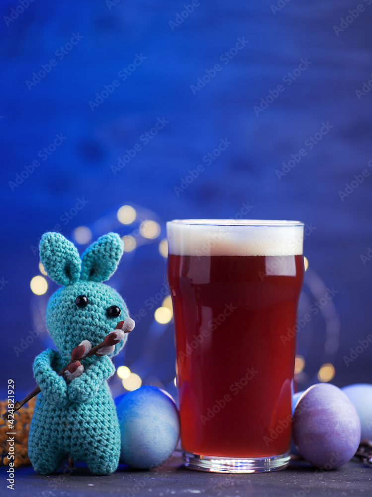 Creative Easter. A glass of craft beer, colored Easter pastel eggs, a bunny with a willow branch - obrazy, fototapety, plakaty 