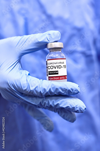 Female doctor in blue gloves holding COVID-19 vaccine. Healthcare and Medical concept. Selective focus photo