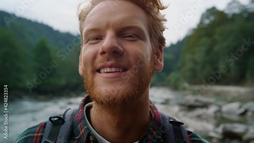 Hiker standing in mountain landscape. Redhead man looking at camera outdoor photo