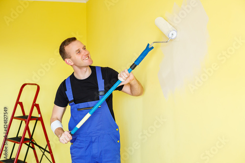 A young man makes repairs to the apartment, ok re-paints the walls in a different color