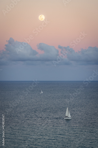 A beautiful setting moon over a sailboat and the Atlantic Ocean. Florida, USA.