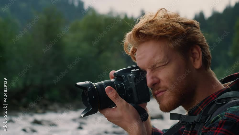 Male photographer taking pictures of nature. Redhead man using photo camera Male photographer taking pictures of nature. Redhead man using photo camera