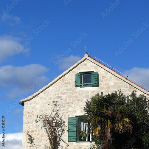 Traditional Mediterranean house with wooden window shutters and flowers.