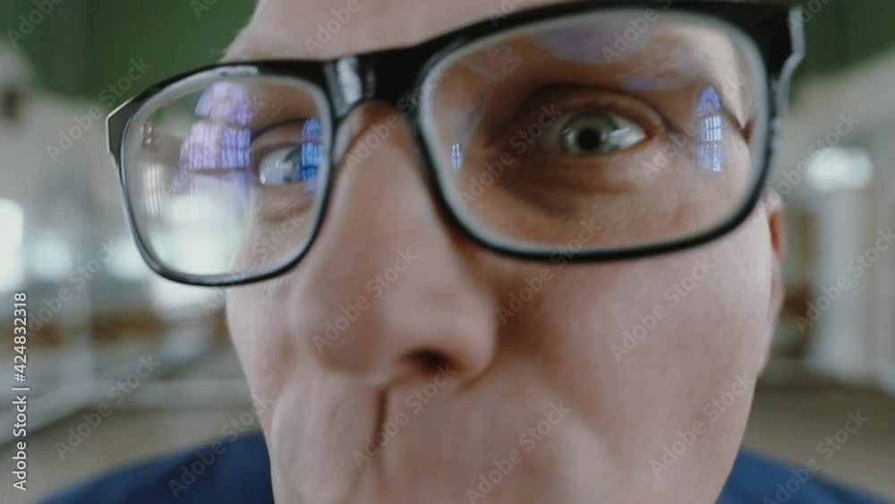 A young guy with glasses funny and emotional looks and speaks into the lens of the camera. Businessman fooling around on camera. man grimaces at the camera.