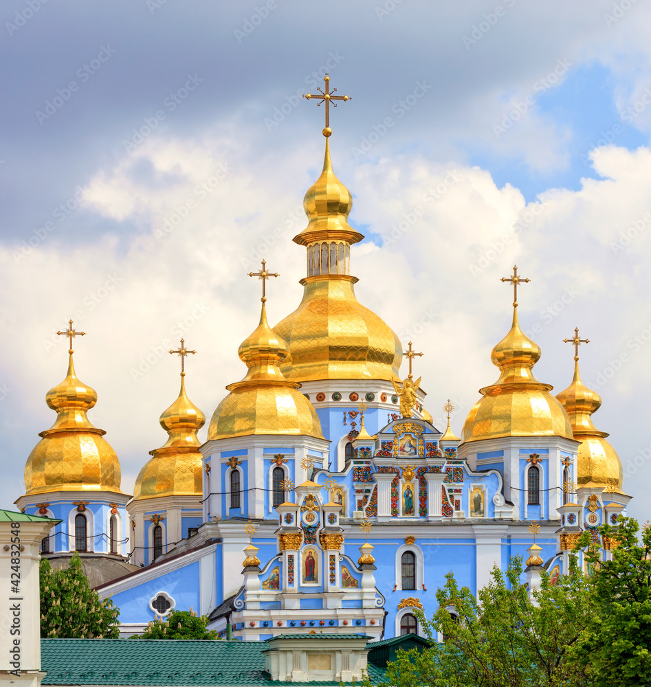 Golden domes of St. Michael's Golden-Domed Cathedral in Kiev in the spring against a blue cloudy sky on a warm spring day.