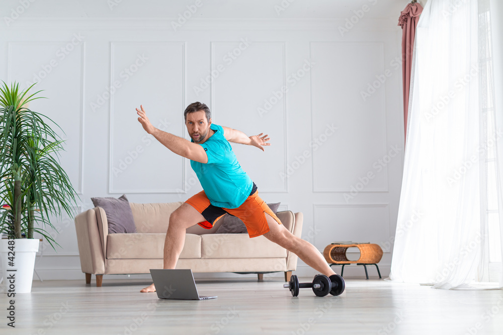 Photo pf a middle-aged man during online aerobic workout. Home workout concept. Photo pf a middle-aged man during online aerobic workout. Home workout concept.