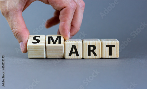 Smart art symbol. Businessman turns cubes and changes the word 'smart' to 'art'. Beautiful grey table, grey background. Business and smart art concept, copy space.