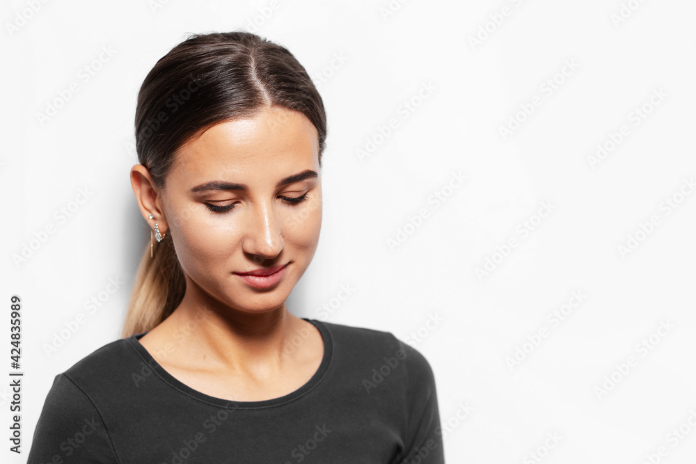 Studio portrait of young brunette girl looking down on white background. Studio portrait of young brunette girl looking down on white background.