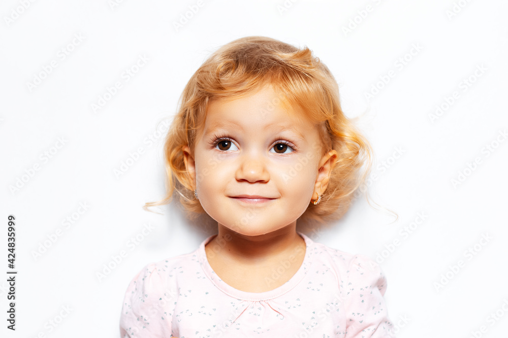 Studio portrait of cheerful child girl with curly blonde hair, looking up on background of white color. Studio portrait of cheerful child girl with curly blonde hair, looking up on background of white color.