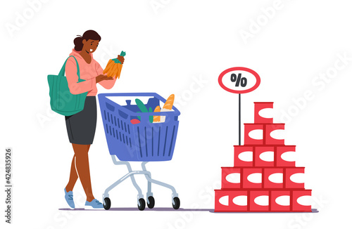 Customer in Grocery or Supermarket with Goods in Shopping Trolley Holding Bunch of Carrot in Hand. Woman Visiting Store