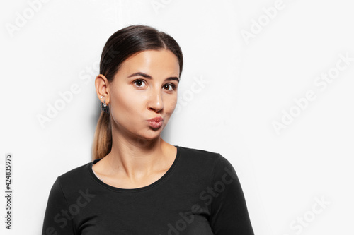 Studio portrait of young brunette girl send air kiss on white background.