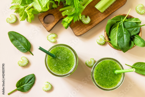 Vegan smoothie recipe. Healthy diet and nutrition, vegan and alkaline drink. Green fresh smoothie with celery and spinach on a pink background. Top view. Flat lay.