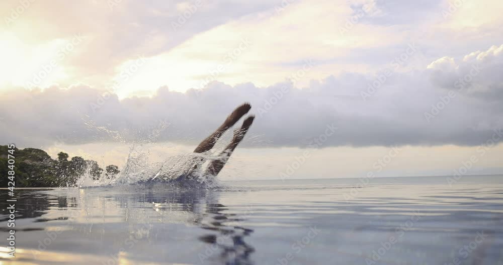 Handsome fit man jumping in the pool water outdoor by the beach