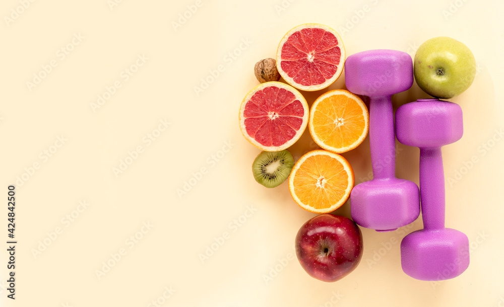 Fresh fruits with sports dumbbell on a yellow background. Motivation and diet plan top view Fresh fruits with sports dumbbell on a yellow background. Motivation and diet plan top view