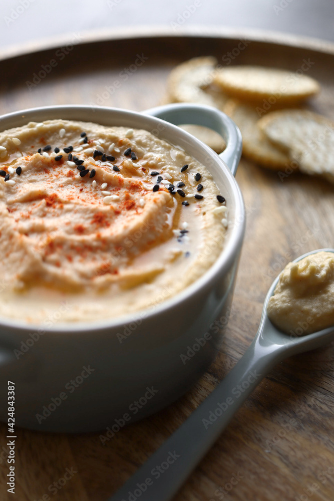 Hummus with light and dark sesame seeds and crackers in the background Hummus with light and dark sesame seeds and crackers in the background