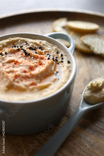 Hummus with light and dark sesame seeds and crackers in the background