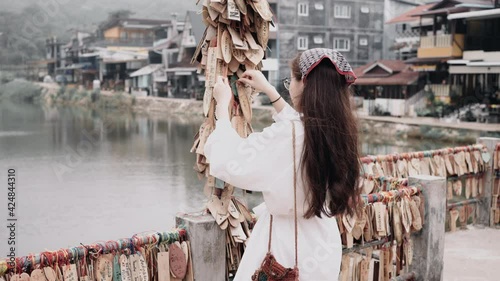 White dress woman fastening the wood plate to the bridge rail in E-Tong village Pilok Thongphaphum Kanchanaburi, Thailand. photo