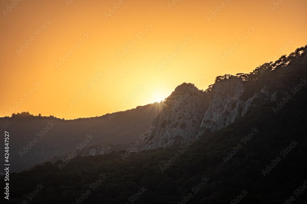 Sunset in the mountains among the green trees