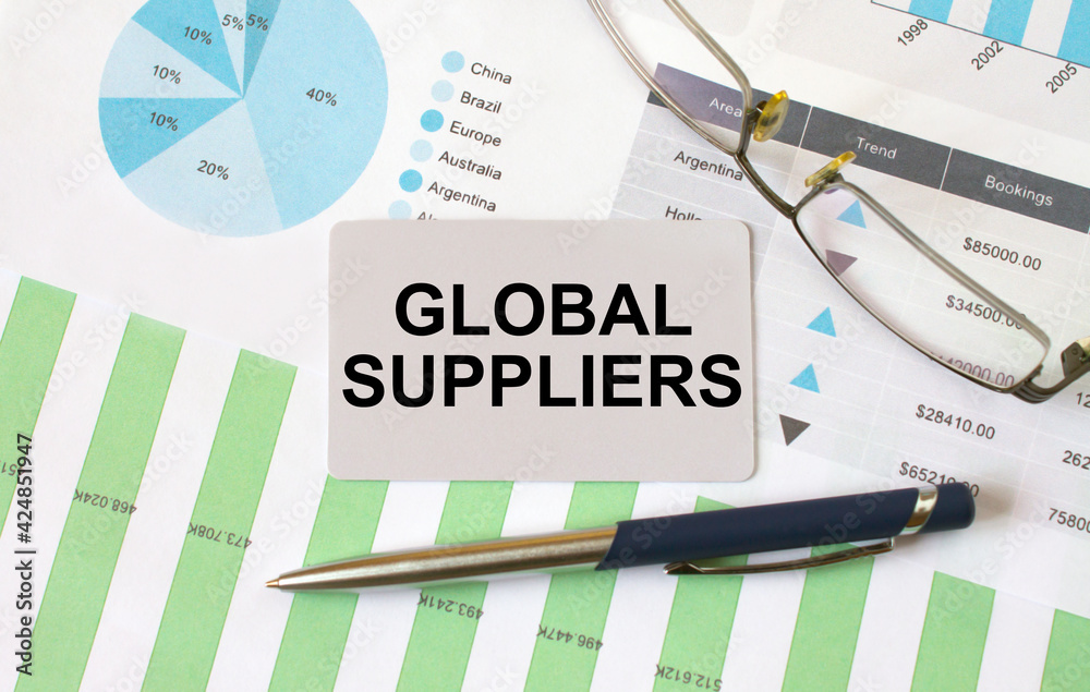 Business card with text Global Suppliers lies on financial charts with pen and eyeglass Business card with text Global Suppliers lies on financial charts with pen and eyeglass