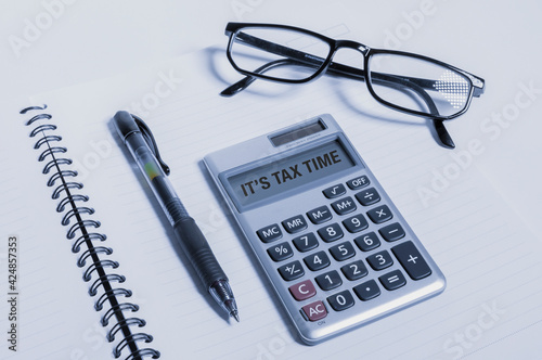 Tax day text written on calculator next to a pen and glasses on top of a  notebook. Stock Photo | Adobe Stock